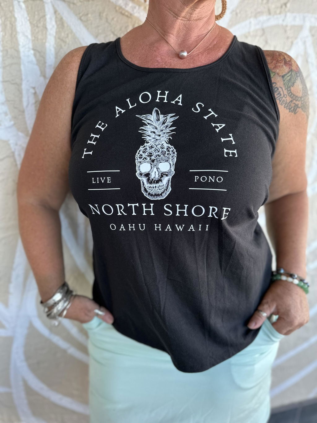 Customer wearing a black tank top with crisp white lettering and detailed pineapple artwork