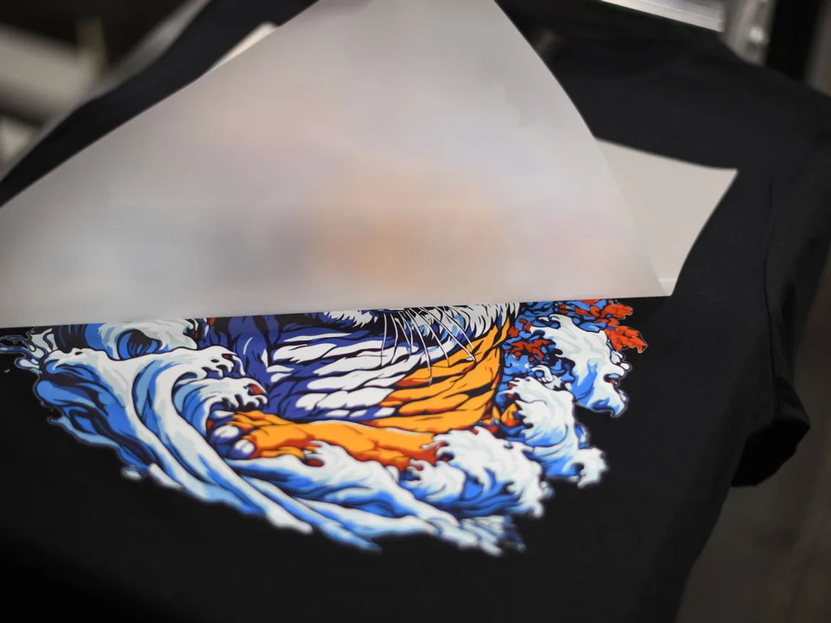 Detailed tiger artwork revealed as transfer film is peeled from a black shirt